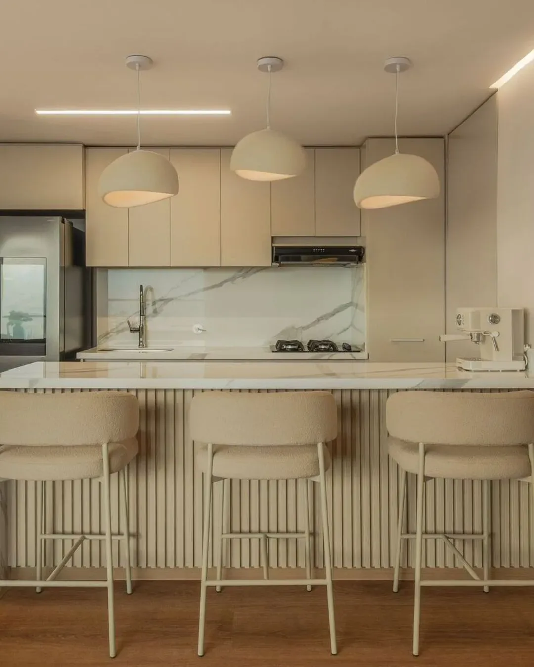 Cocina integrada con sillas tapizadas y una estética limpia, cálida y contemporánea