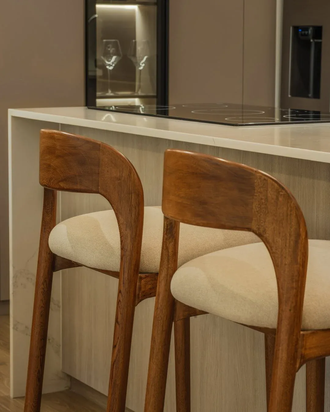 Detalle en primer plano de dos taburetes de barra de diseño, con respaldos curvos de madera maciza