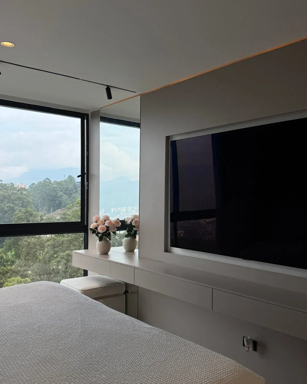 Mueble flotante con televisión integrada, espejo y floreros decorativos, con vistas a la montaña.