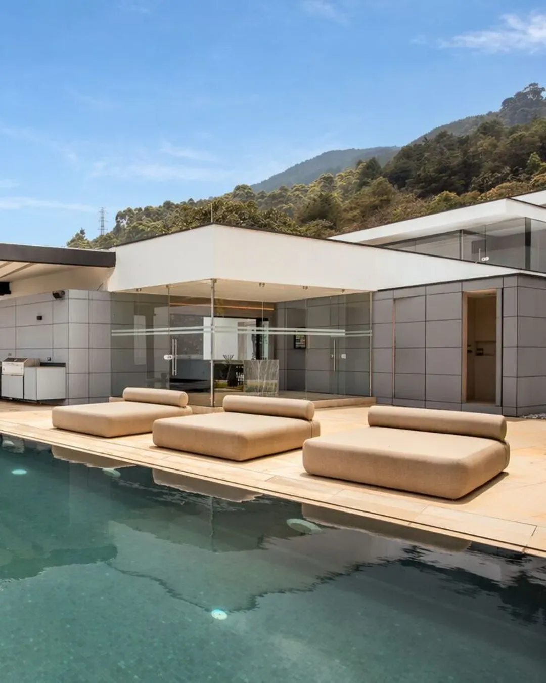Zona exterior con camastros acolchados, piscina y arquitectura integrada al paisaje.