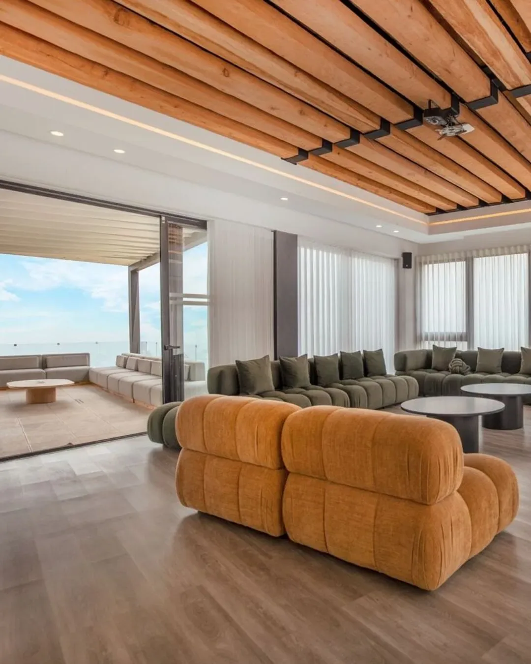 Sala amplia con sofás voluminosos, madera natural y vistas abiertas al paisaje.