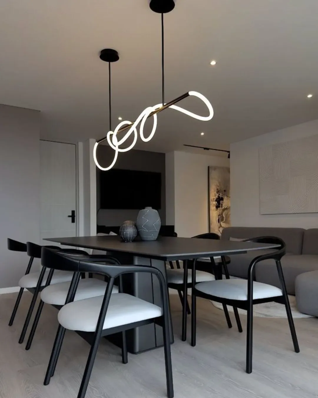 Comedor protagonista con diseño negro, lámpara escultórica y una estética masculina sofisticada.
