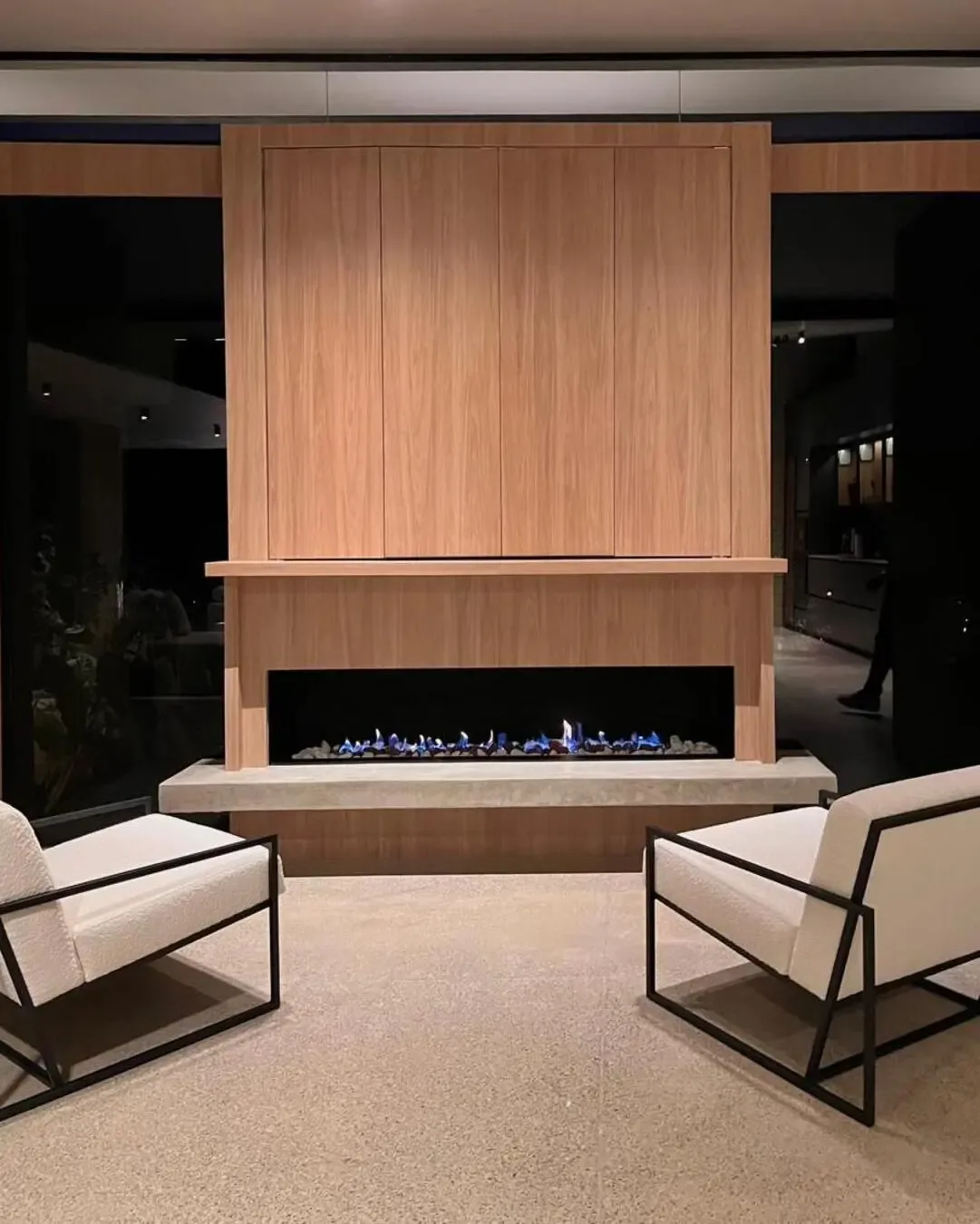Chimenea central con sillas tapizadas, madera natural y una atmósfera cálida y sofisticada.