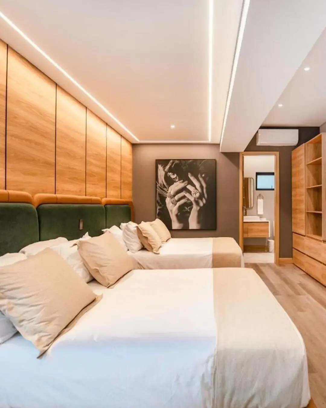 Habitación cálida con camas dobles, cabecero tapizado, madera natural y detalles acogedores.