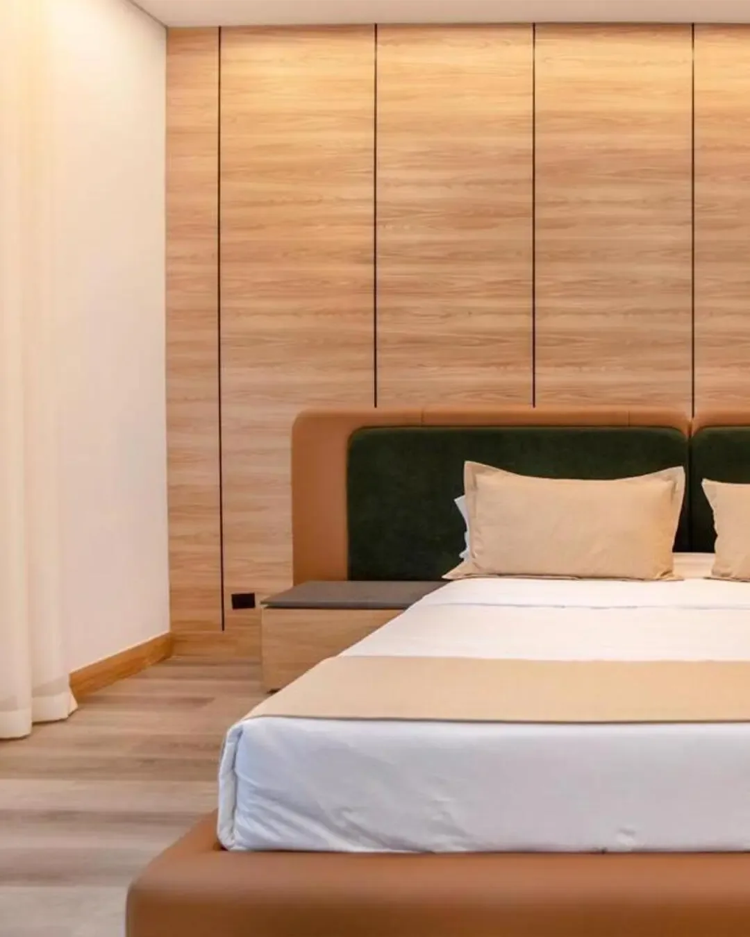 Cama hotelera con cabecero tapizado, madera envolvente y una atmósfera cálida de descanso.
