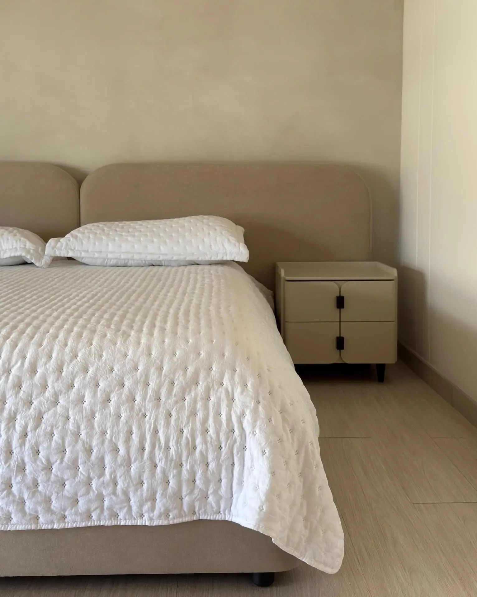 Neutral bedroom with upholstered bed, functional nightstand, and a clean aesthetic.
