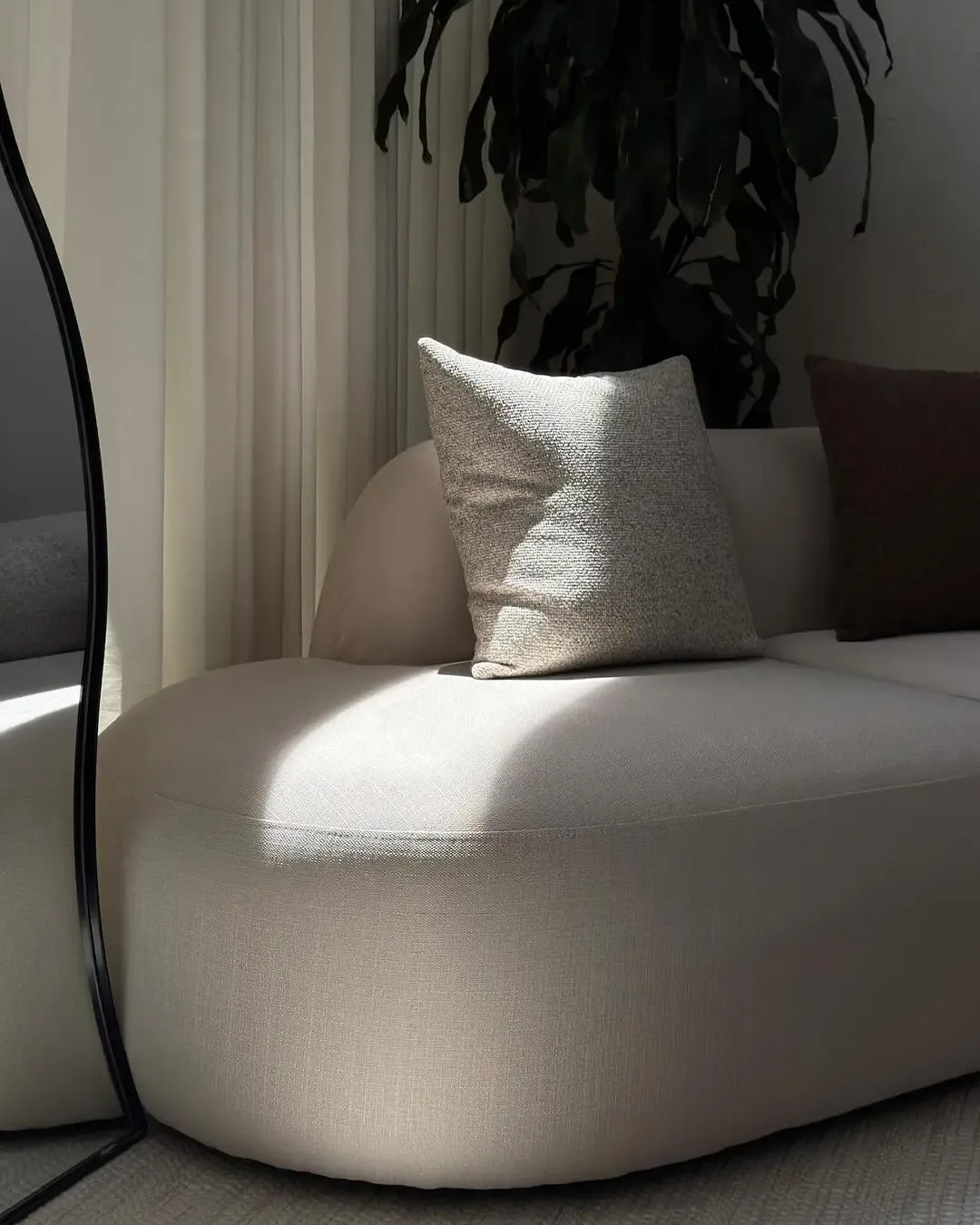 Curved sofa with textured cushions, natural light, and a soft serene atmosphere.