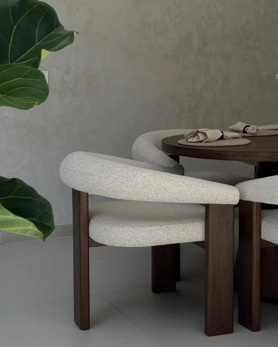 Enveloping dining chair with solid wood, light upholstery, and organic details.Enveloping dining cha