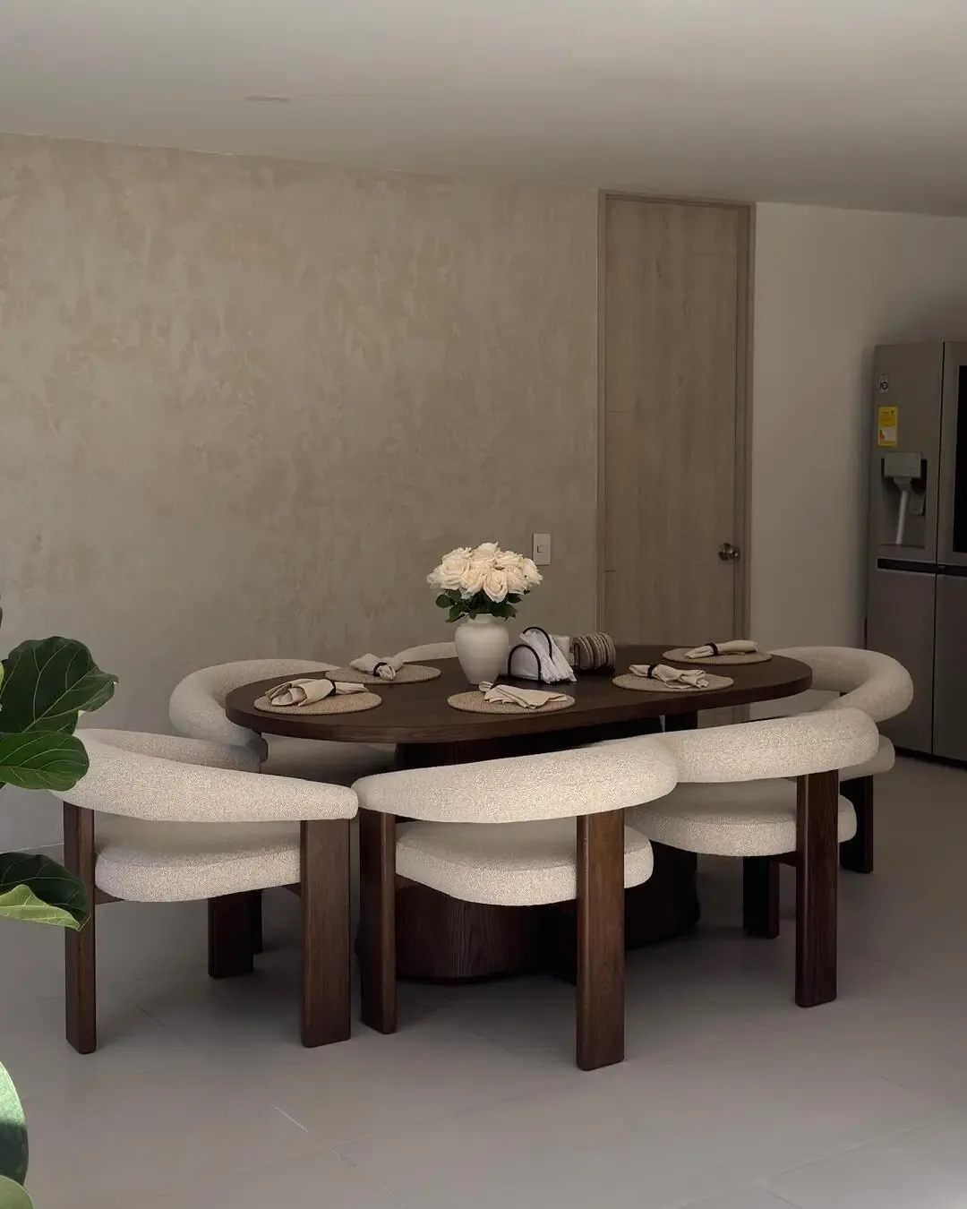 Warm dining room with curved chairs, wooden table, and elegant natural composition.