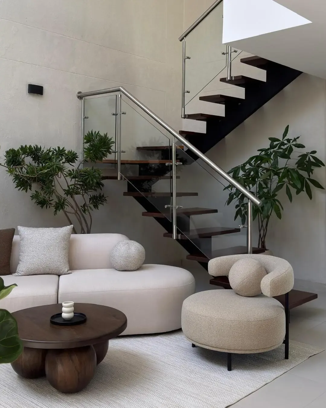 Organic living room with curved sofa, upholstered chair, wooden table, and indoor greenery.