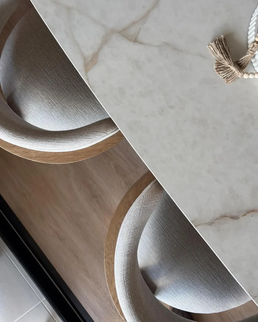 Detalle de comedor con superficie clara, sillas curvas y materiales cuidadosamente integrados.