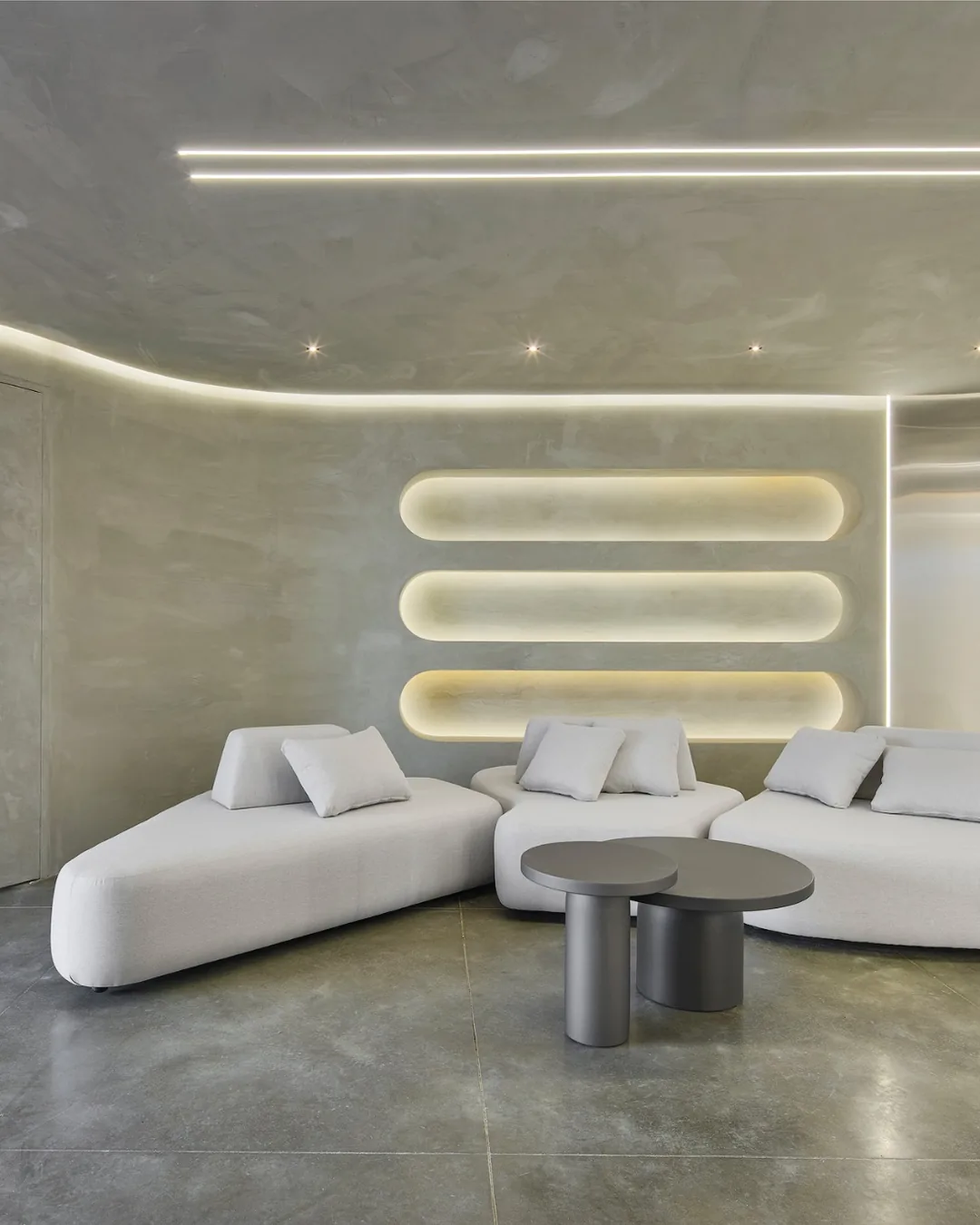 Espacio abierto con sofás modulares, sillones en tono verde suave, panel en madera natural e ilumina