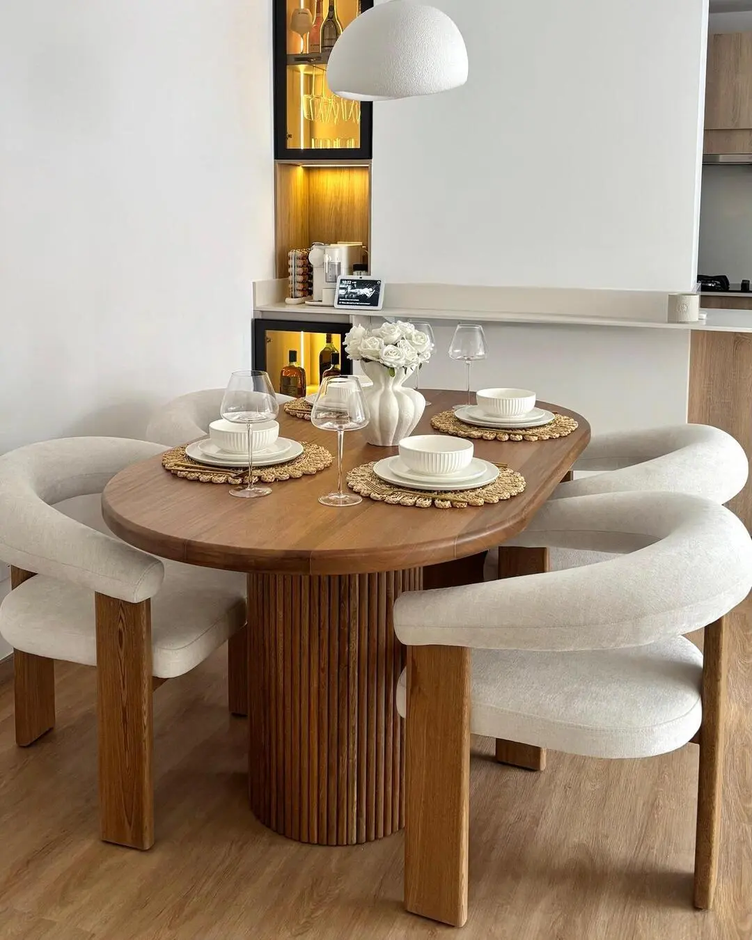 Juego de comedor completo con mesa de madera ovalada y cuatro sillas tapizadas de diseño curvo.