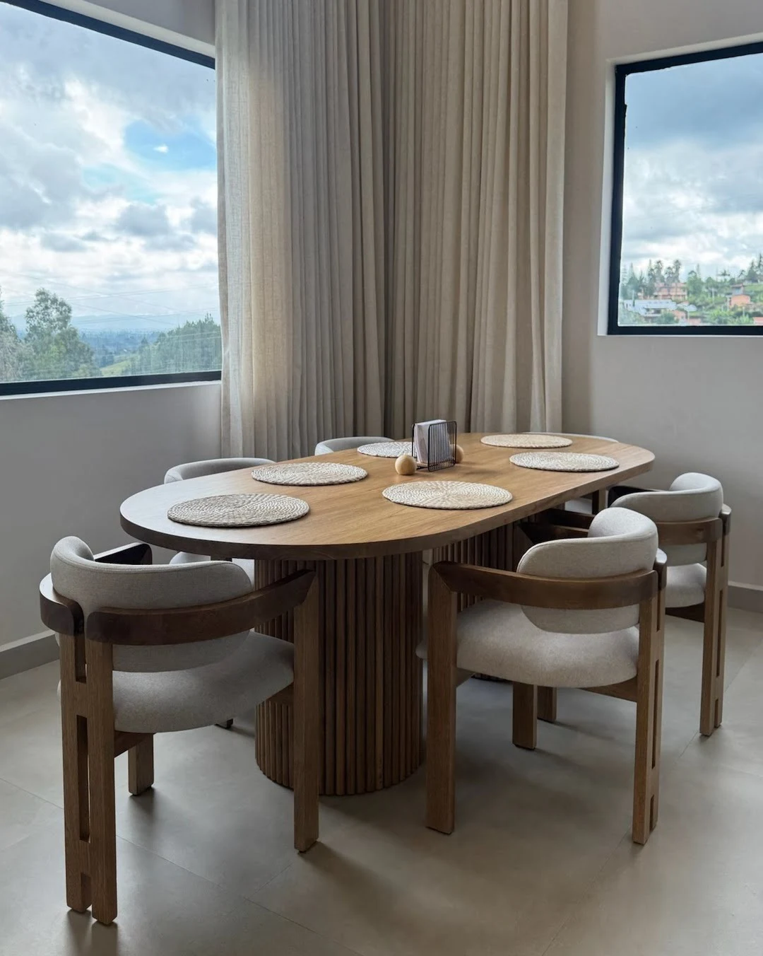 Mesa de comedor de madera iluminada por luz natural proveniente de un gran ventanal.