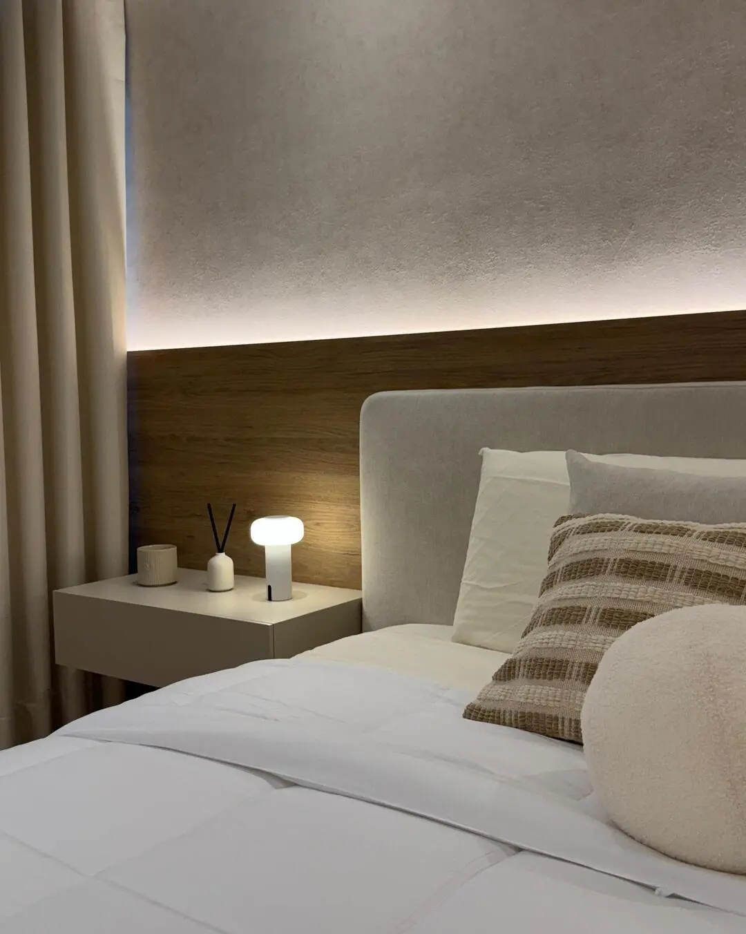 Detalle de la cabecera de la cama y mesa de noche con una lámpara de diseño y un difusor de aroma.