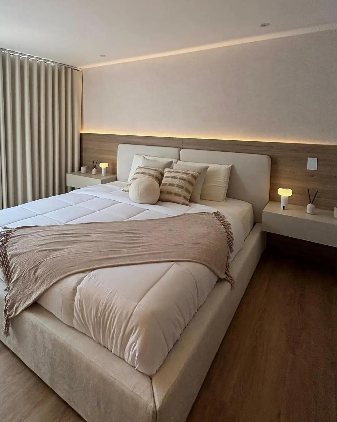 Dormitorio principal con una cama amplia, cabecero de madera con iluminación LED y mesas de noche mi