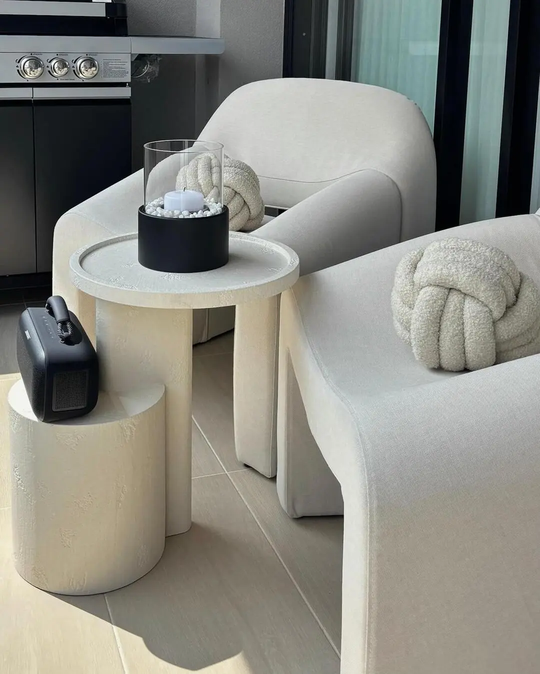 Dos poltronas blancas de diseño moderno en una terraza, decoradas con cojines en forma de nudo.