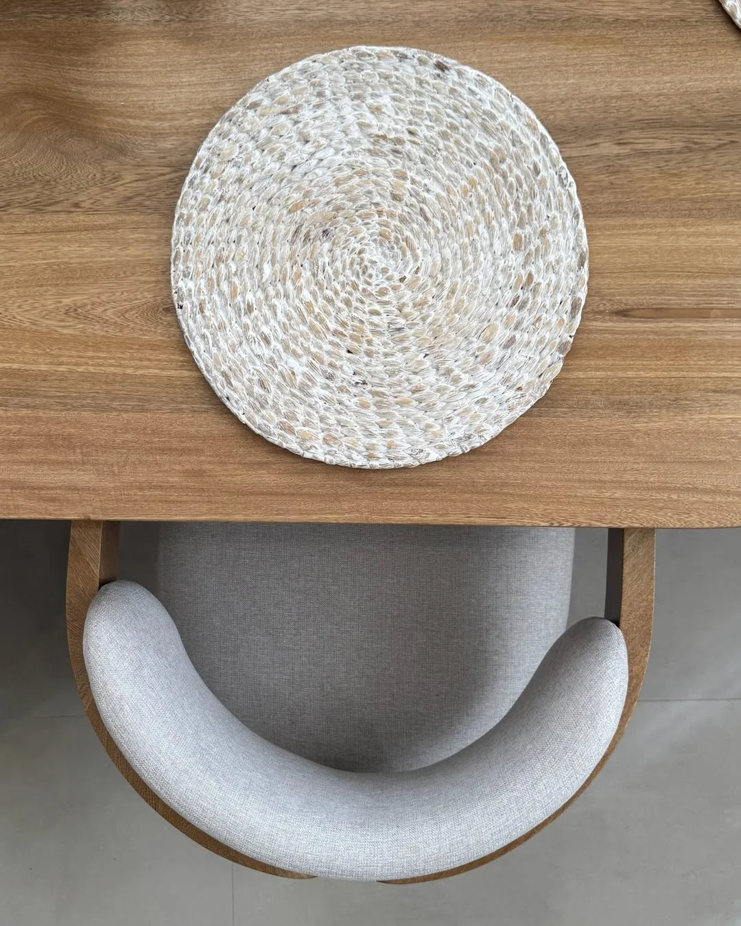 Vista superior de un puesto en la mesa de comedor con un individual de fibra natural sobre madera.